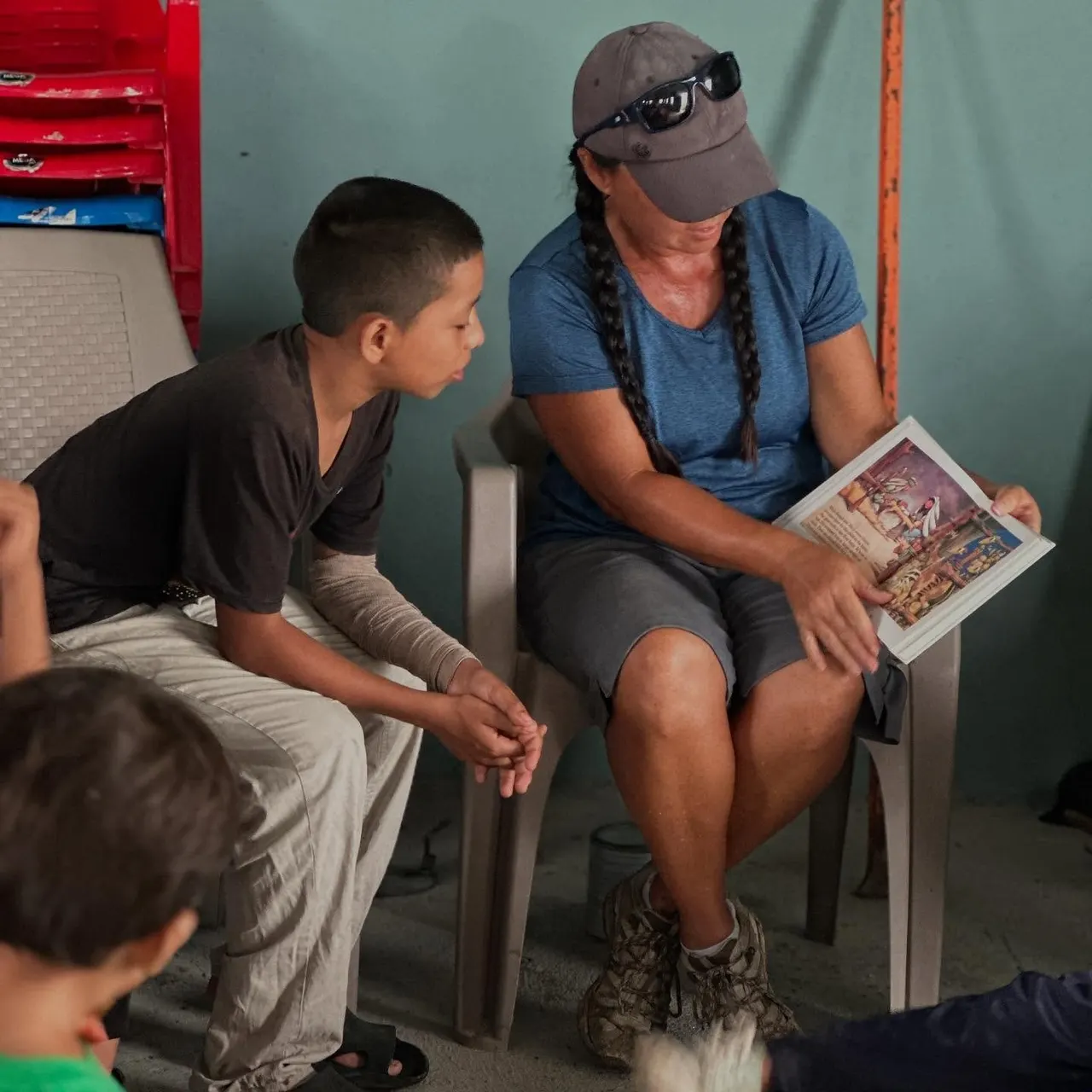A team member reading a picture book with a child during a Honduras summer school session
