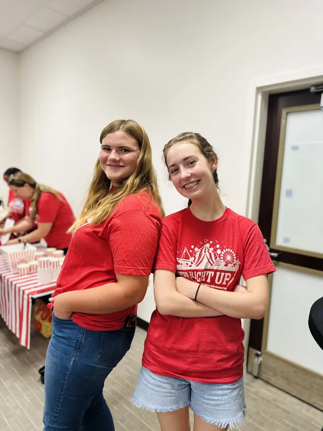 Two student volunteers in red serve team shirts at a church event